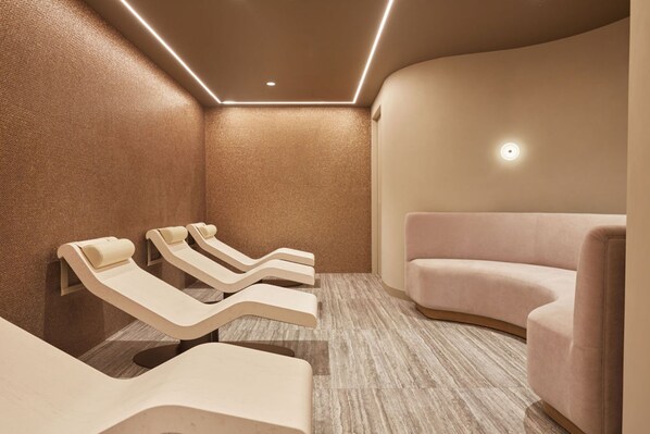 A modern spa room with three massage chairs and a single sofa.