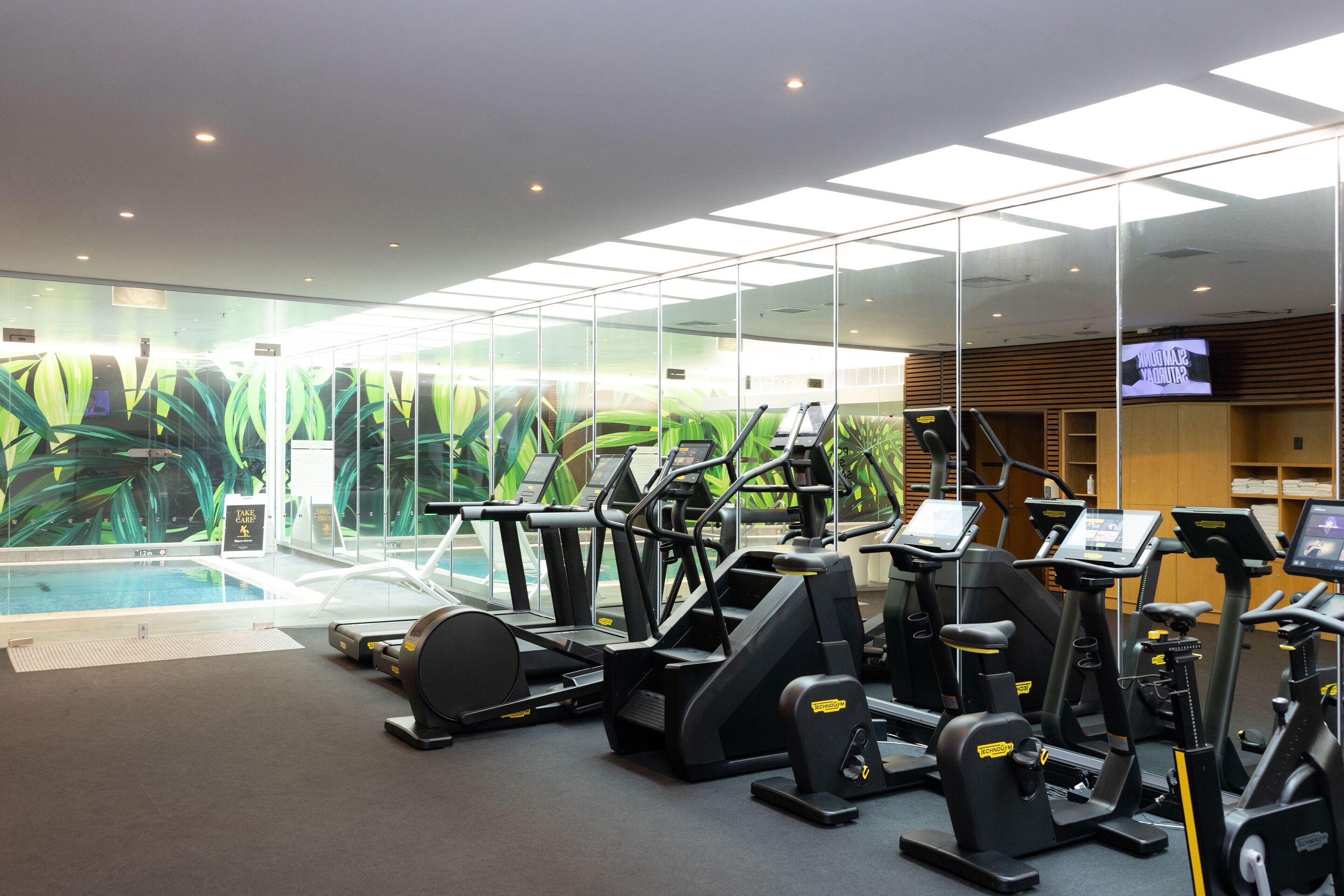 Un gimnasio con cintas de correr, elípticas y una piscina.