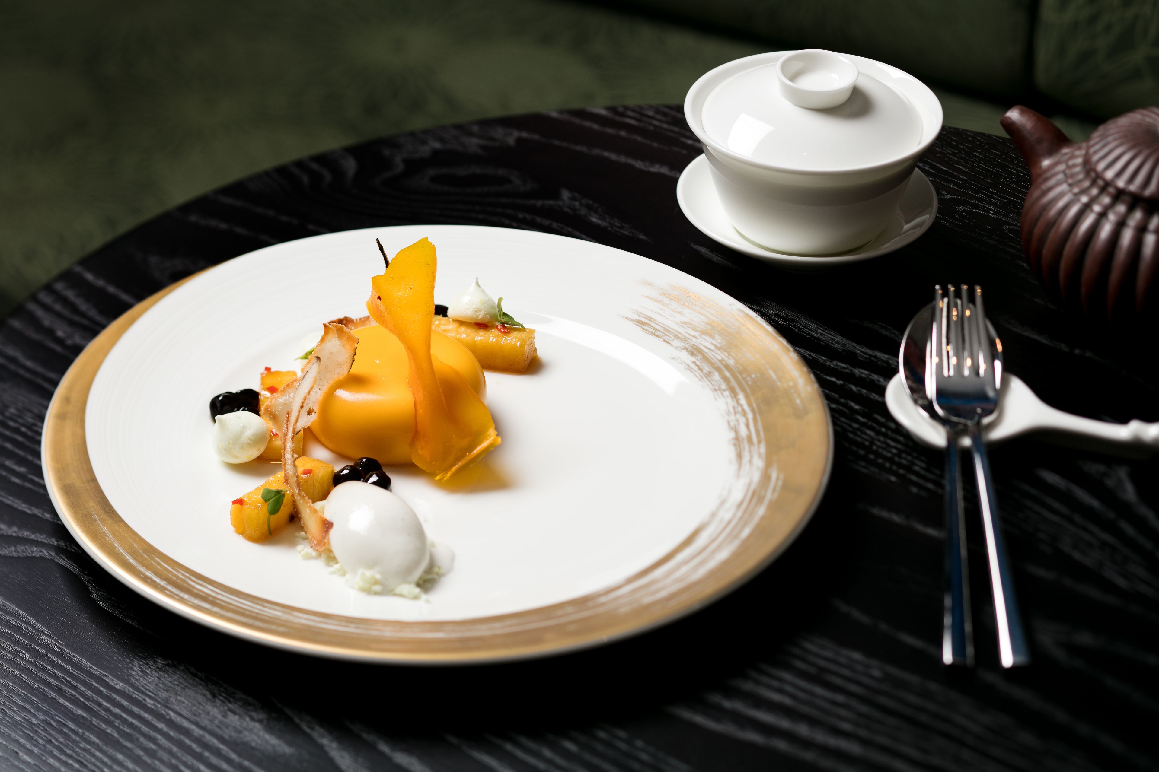 A plate of food with a white bowl and teapot on a table.