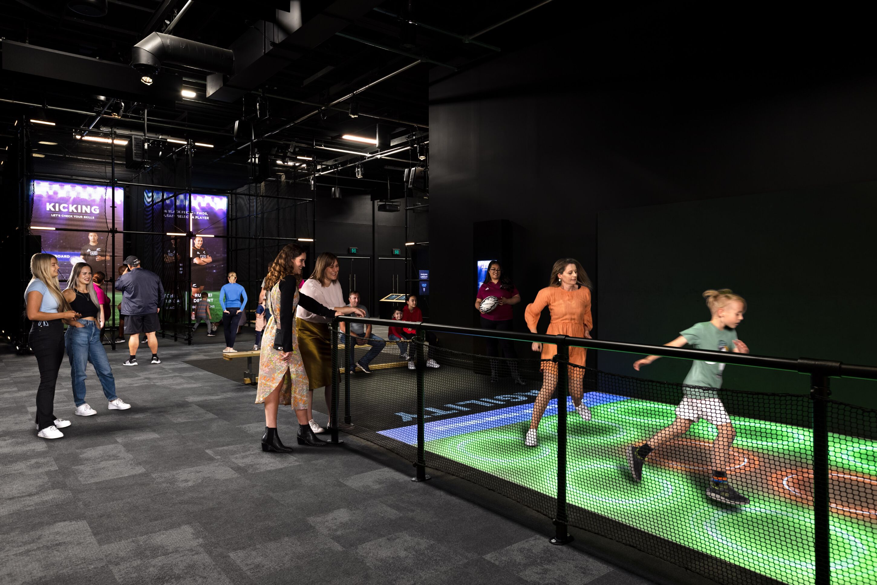 An indoor space with a digital interactive display, a seating area, and a group of people.