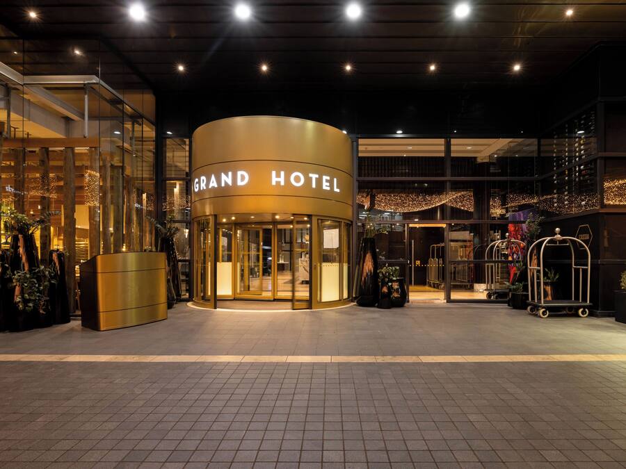 Ein Hotel mit gewölbter Fassade, Glastüren und einem Schild mit der Aufschrift "GRAND HOTEL".