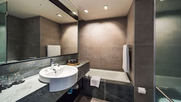 A modern bathroom with a large mirror, a sink, and a bathtub.