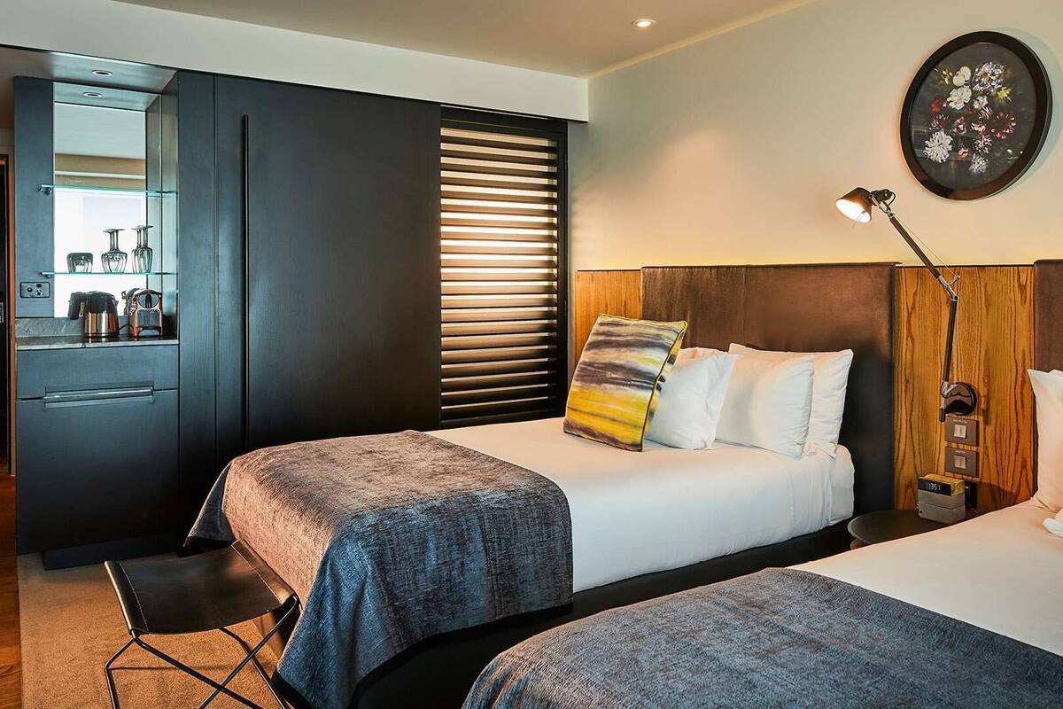 A hotel room with two beds, a desk, and a mirror.