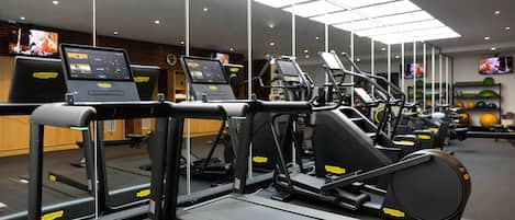 A gym with treadmills, elliptical machines, and exercise balls.