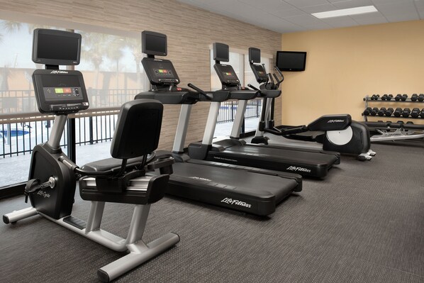 Un gimnasio con cintas de correr, elípticas y máquinas de pesas.