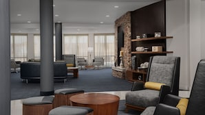 A modern lounge area with a stone accent wall, comfortable seating, and a flat-screen TV mounted above a wooden shelf. - Courtyard by Marriott Panama City (Panama City)
