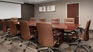 A conference room with a large table and eight brown chairs with wheels.