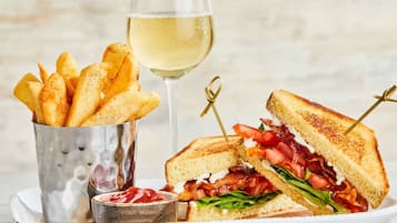 Un sandwich accompagné d’une portion de frites et d’un verre de vin blanc.