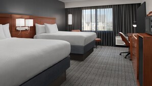 A hotel room with two beds, a desk, a chair, a TV, and a large window with curtains. - Courtyard by Marriott Panama City (Panama City)