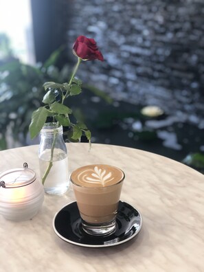 A table with a glass of coffee, a candle, and a vase with a rose. - Pelican Waters Resort (Pelican Waters)