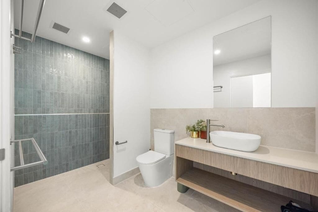A modern bathroom with a shower, toilet, and sink.