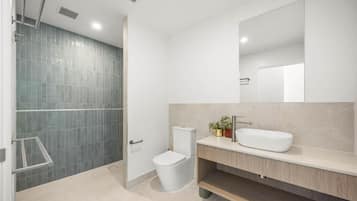 A modern bathroom with a shower, toilet, and sink.