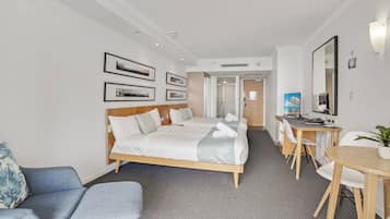 A hotel room with a bed, a desk, a chair, a small table, and a couch.