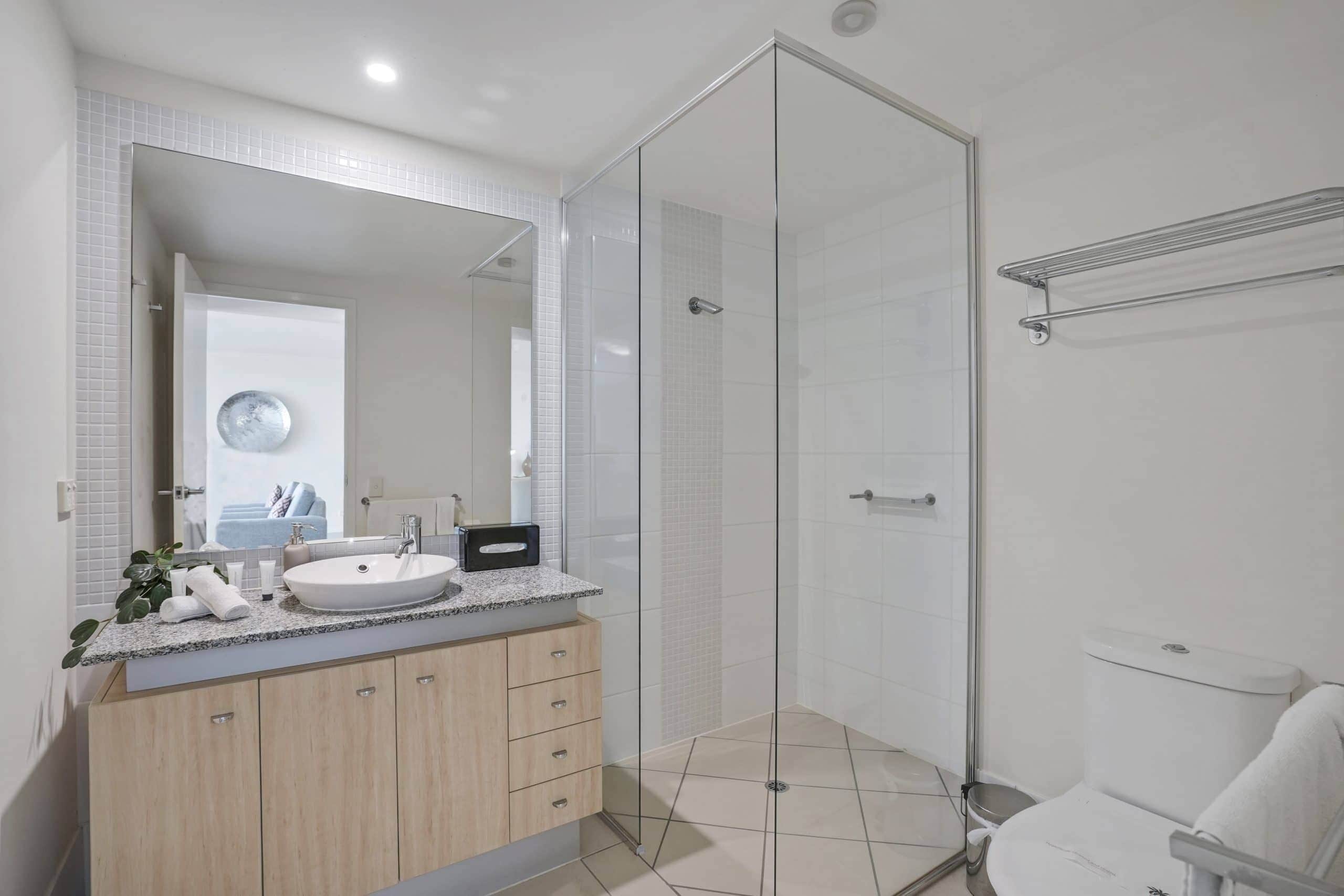A modern bathroom with a glass shower enclosure, a sink with a marble countertop, and a toilet.
