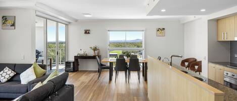 A modern kitchen with a dining area, a sofa, and a view of the outdoors.