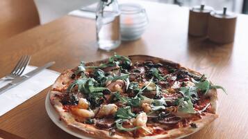 A pizza on a white plate on a wooden table.