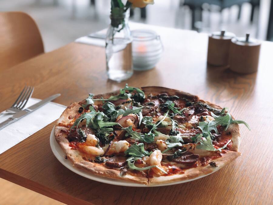 A pizza on a white plate on a wooden table.