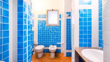 Ein Badezimmer mit blauen Fliesen, einem weißen Waschbecken und einer weißen Toilette.
