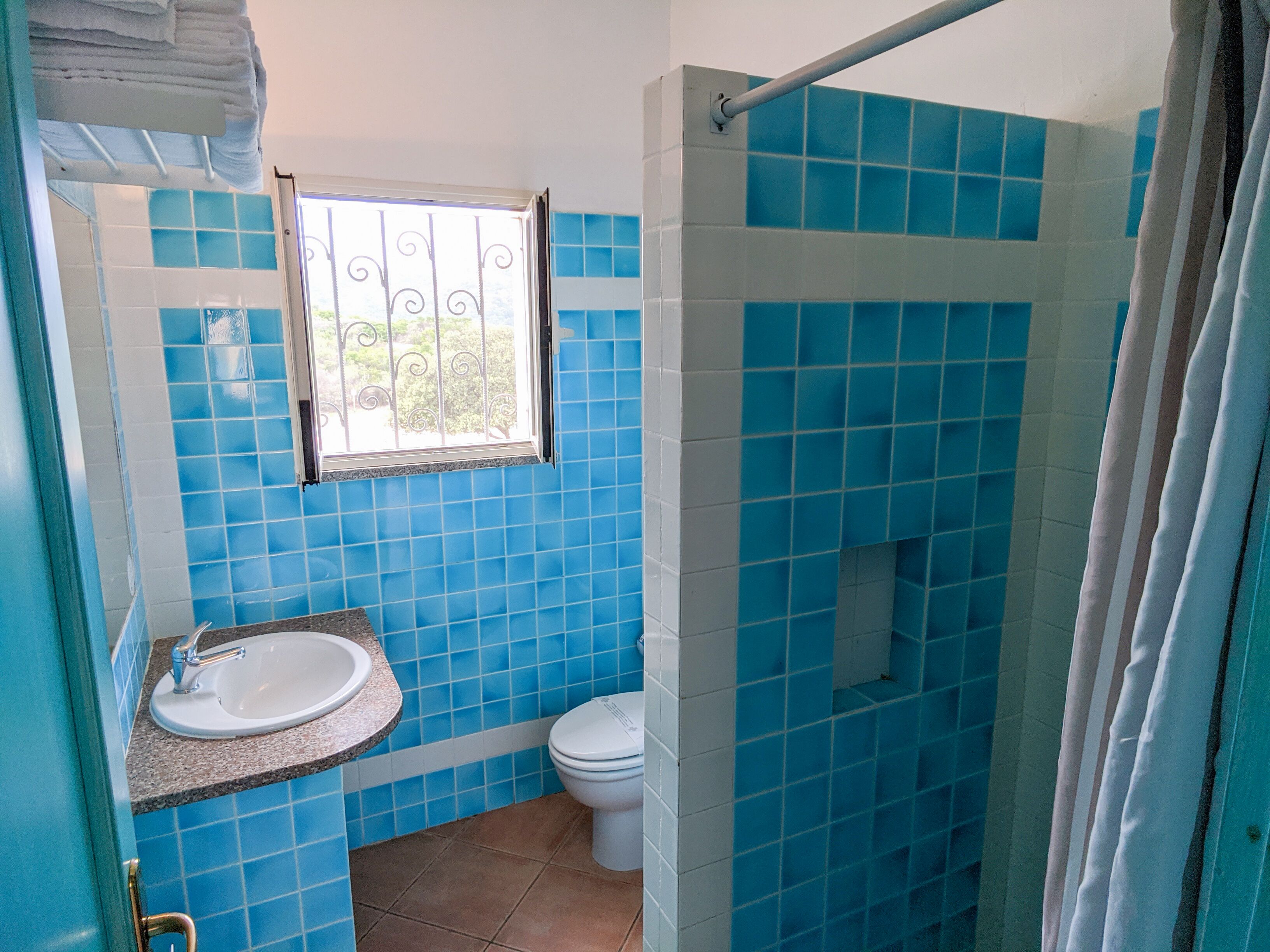A bathroom with blue tiles, a white sink, and a toilet.
