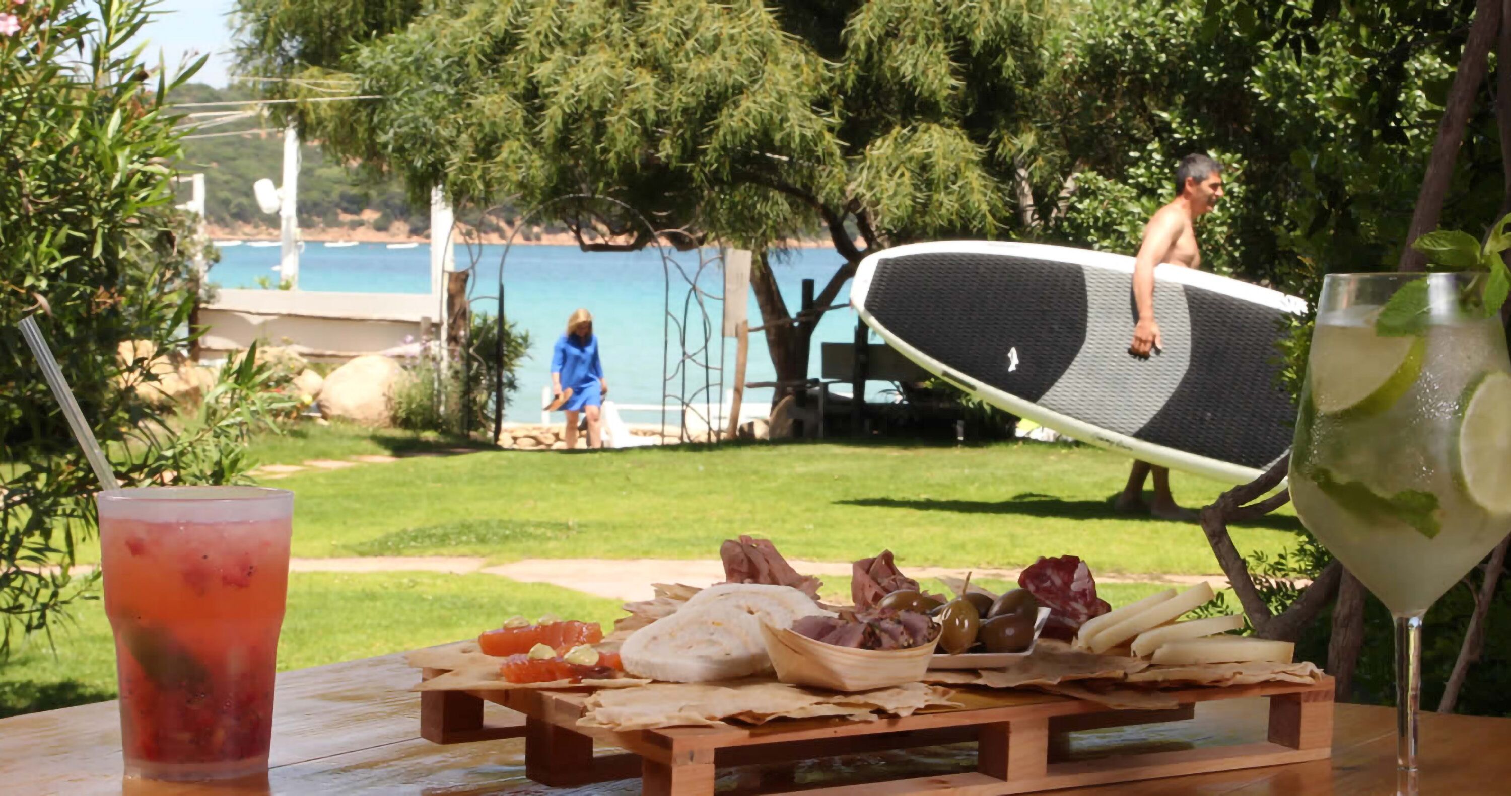 Ein Picknick mit Tisch, Essen und Trinken mit Blick auf Strand und Pool.