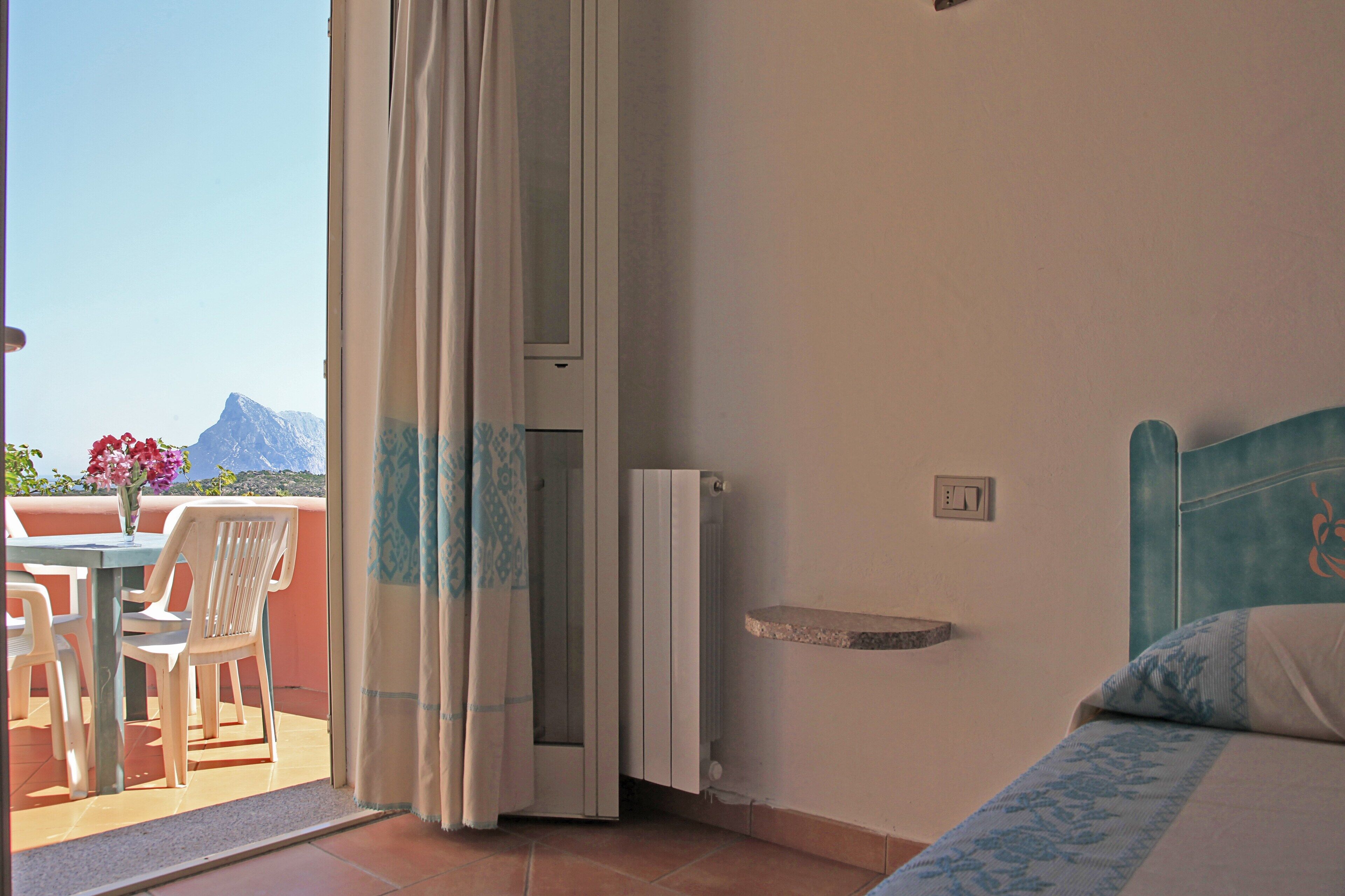 Una habitación con cama, una mesa con sillas y vistas a las montañas.