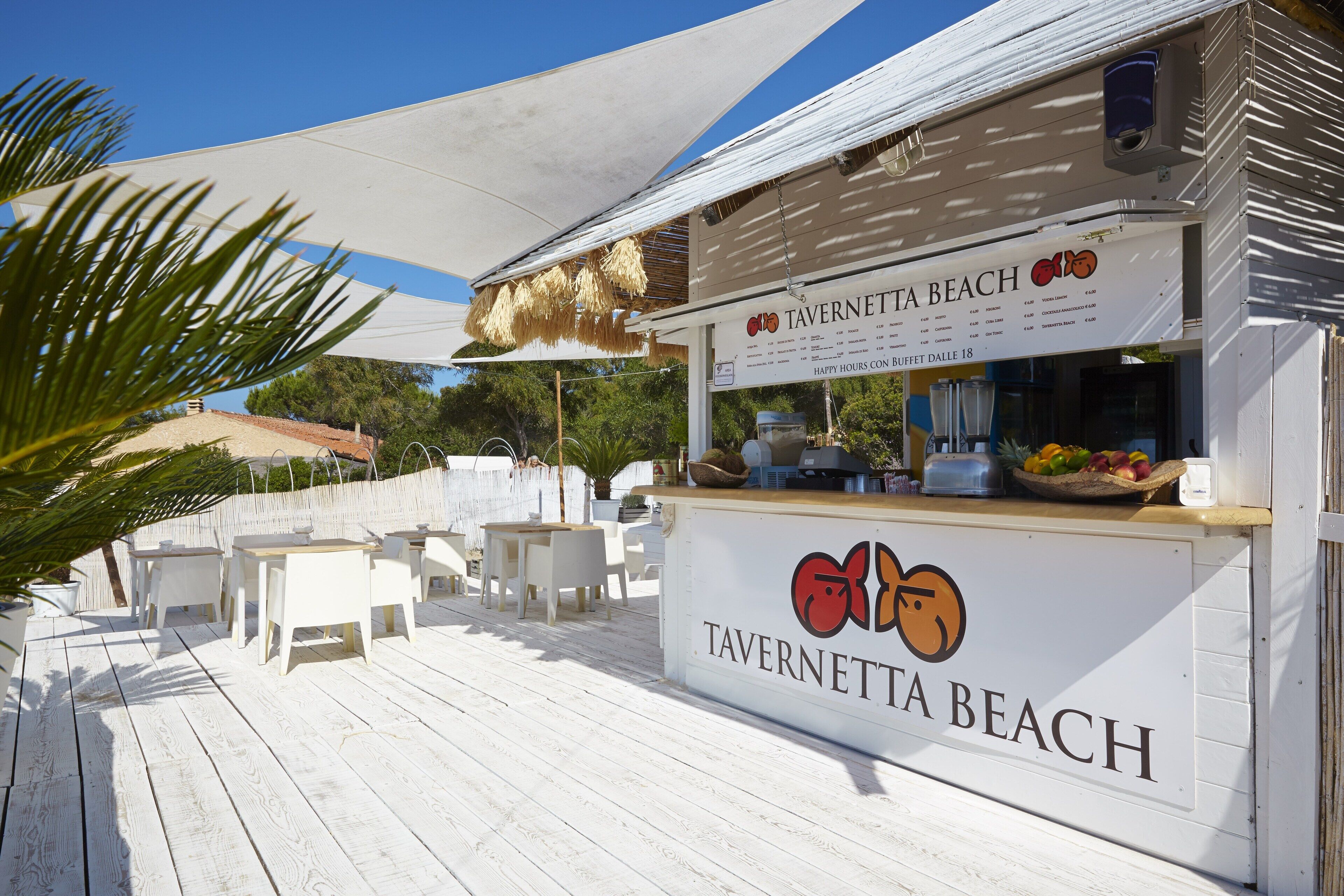 A beachside restaurant named Tavernetta Beach with outdoor seating and a shaded area.