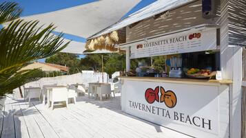Ein Restaurant direkt am Strand namens Tavernetta Beach mit Außenplätzen und einer beschatteten Zone.
