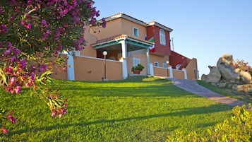 A two-story house with a covered porch, a flag, and a well-maintained lawn.
