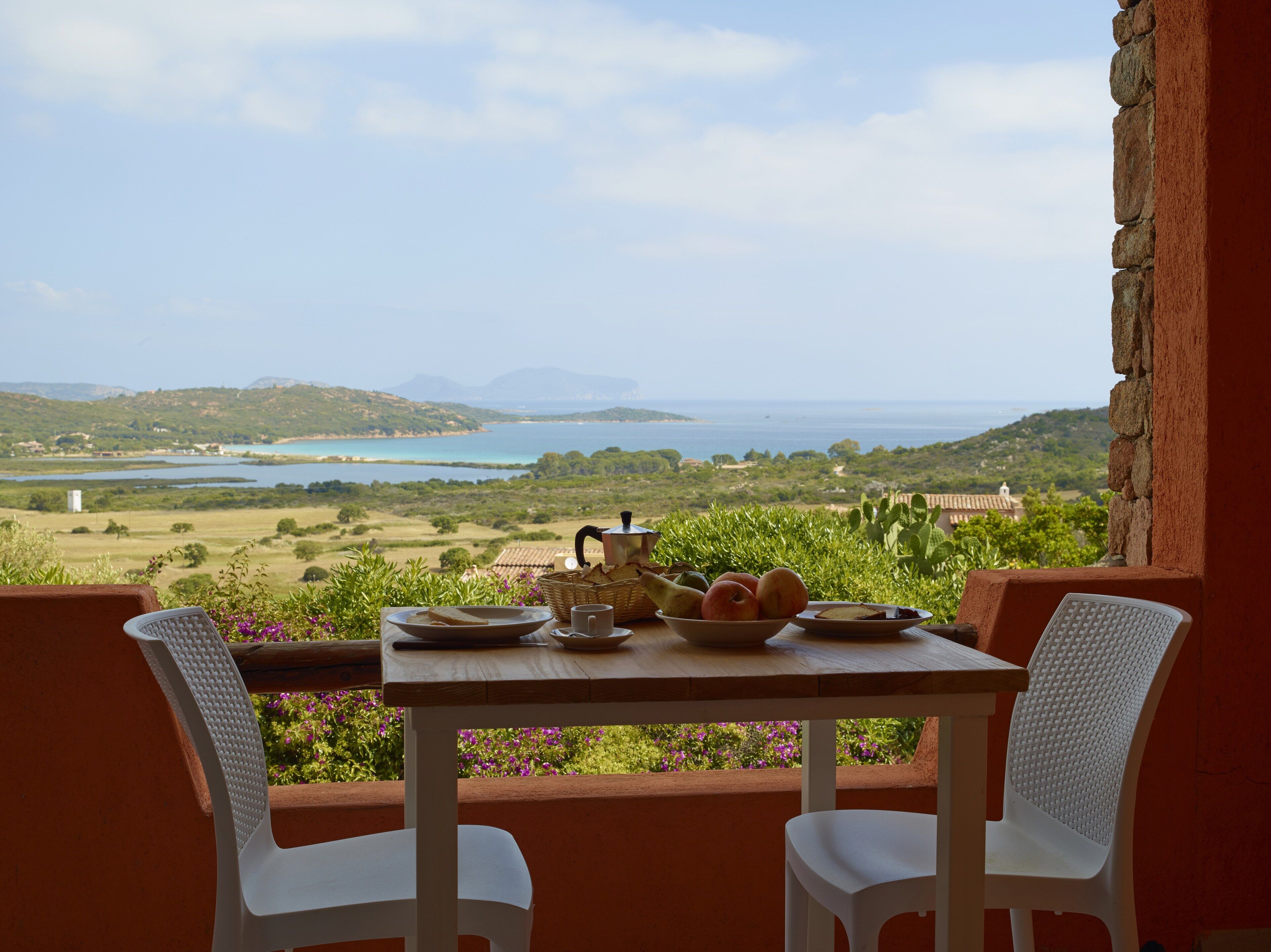 A table with breakfast items and a view of a coastal landscape.