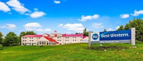 Et Best Western hotel med rødt tag, flere bygninger og en græsplæne.