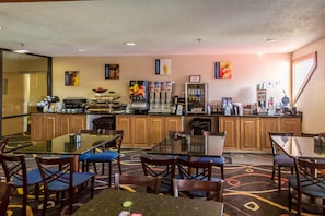 A hotel dining area with multiple tables and chairs, a coffee station, and a refrigerator. - Best Western White Mountain Inn (Franconia)