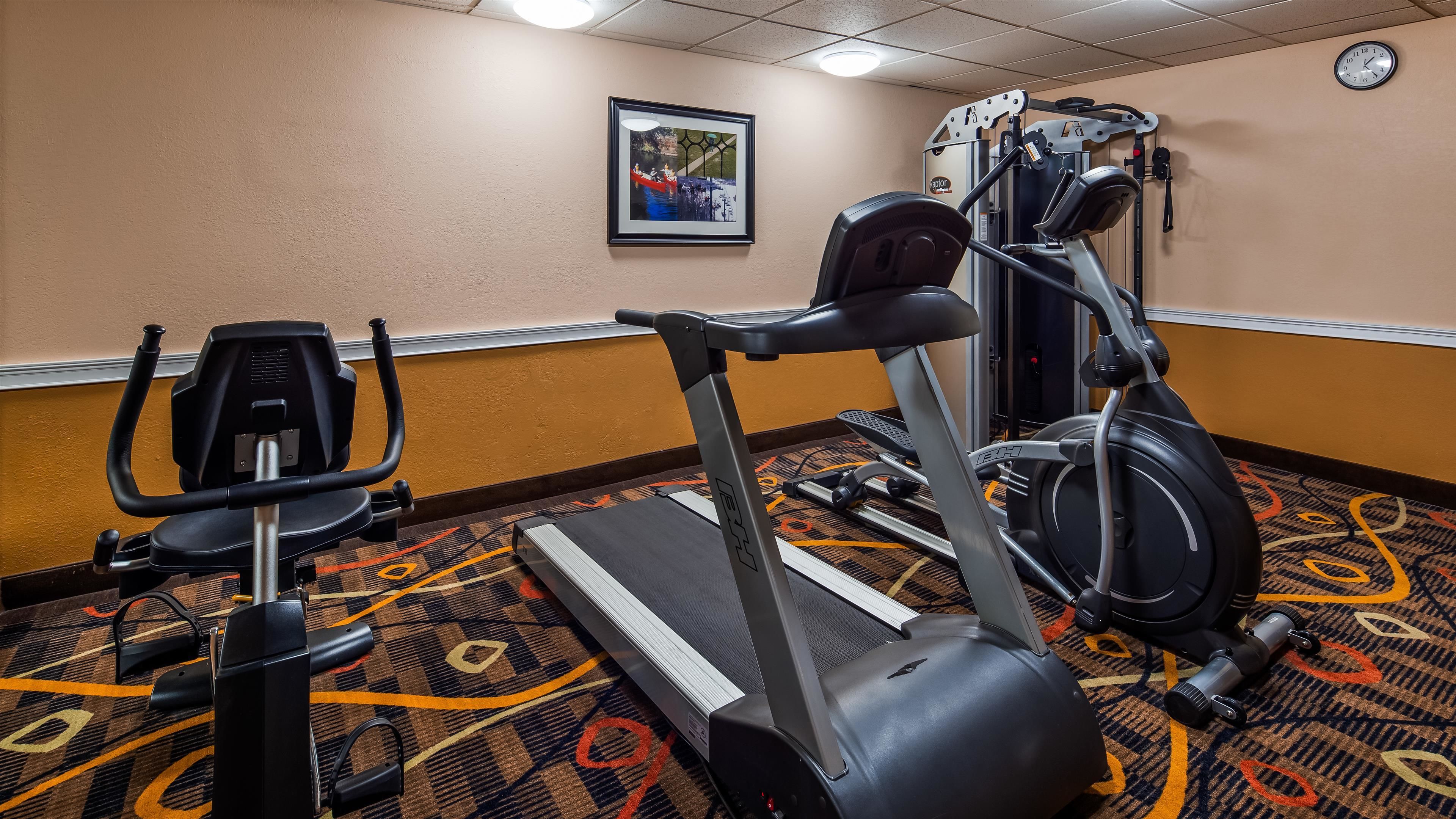 Un gimnasio con cinta de correr, elíptica y máquina de pesas.