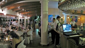Een restaurant met meerdere eettafels, een bar en een barman.