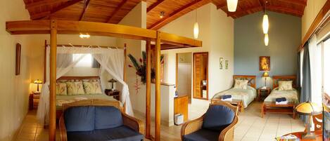 A room with a bed, two chairs, a small table, and a window.
