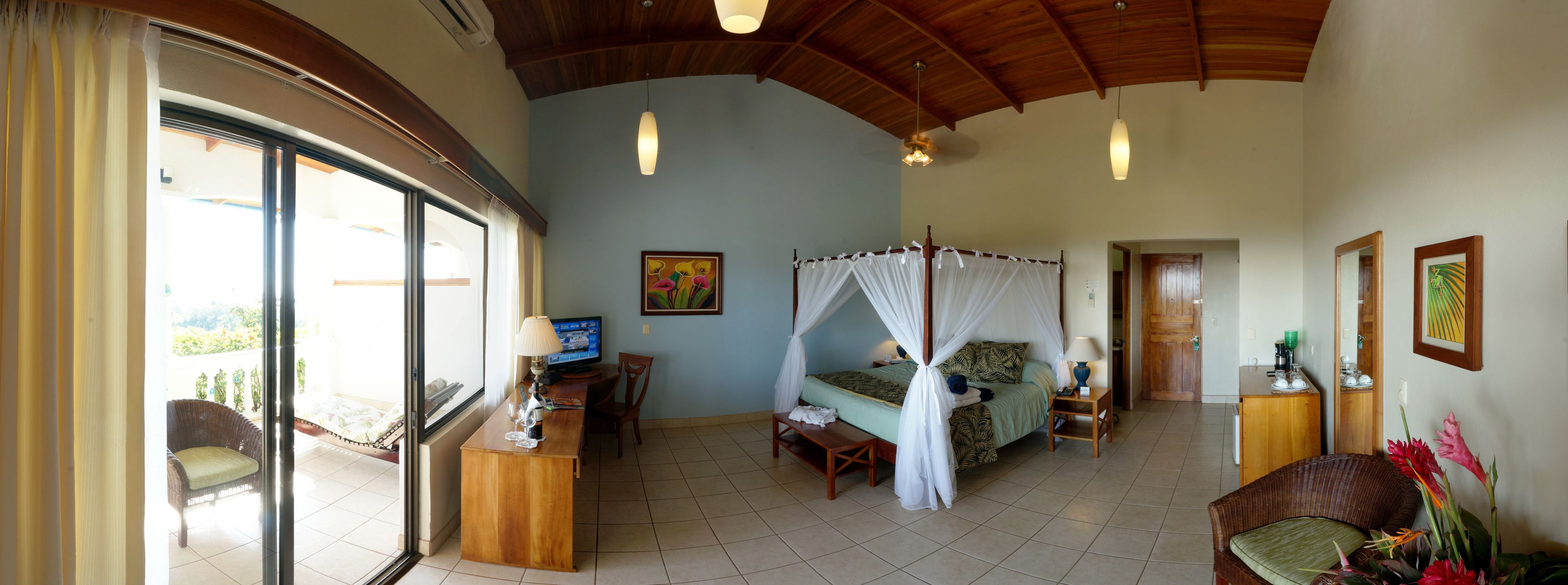 A room with a bed, a desk, a chair, a TV, and a balcony.