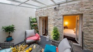 A cozy patio with wicker furniture, a table with candles, and potted plants. - Hôtel Veryste & Spa (Paris)