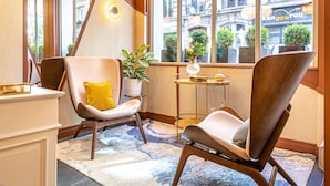 A hotel room with two armchairs, a small table, and a potted plant. - Hôtel Veryste & Spa (Paris)