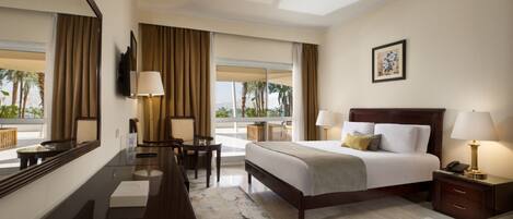 A hotel room with a large bed, a desk, a chair, a TV, and a window with curtains.