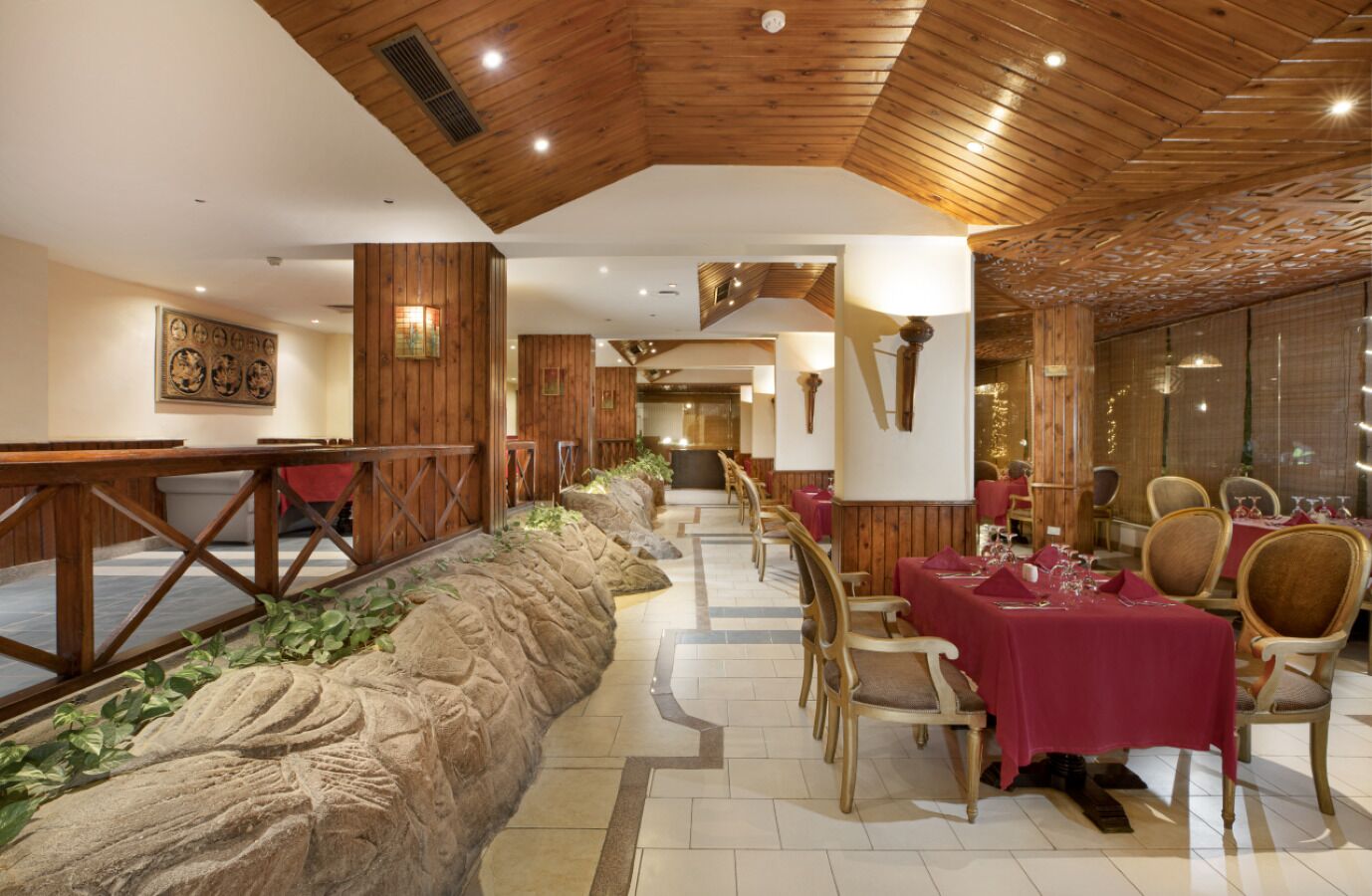 A restaurant with wooden ceiling beams, stone walls, and tables set for dining.