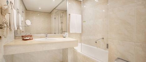 A modern bathroom with a large mirror, a sink, a bathtub, and a toilet paper holder.