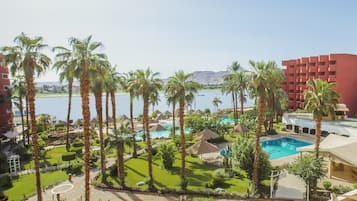 A resort with a swimming pool, palm trees, and a view of the water.