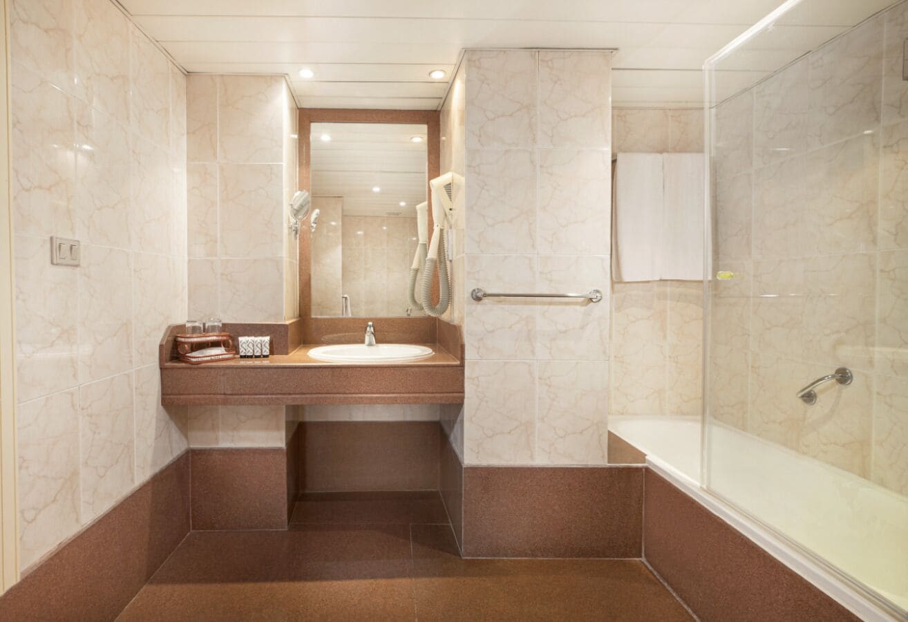 A bathroom with a marble sink, a glass-enclosed shower, and a bathtub.