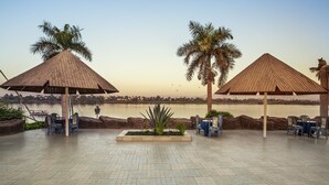 A riverside terrace with wooden canopies, seating, and a view of the river. - Pyramisa Hotel Luxor (Luxor)
