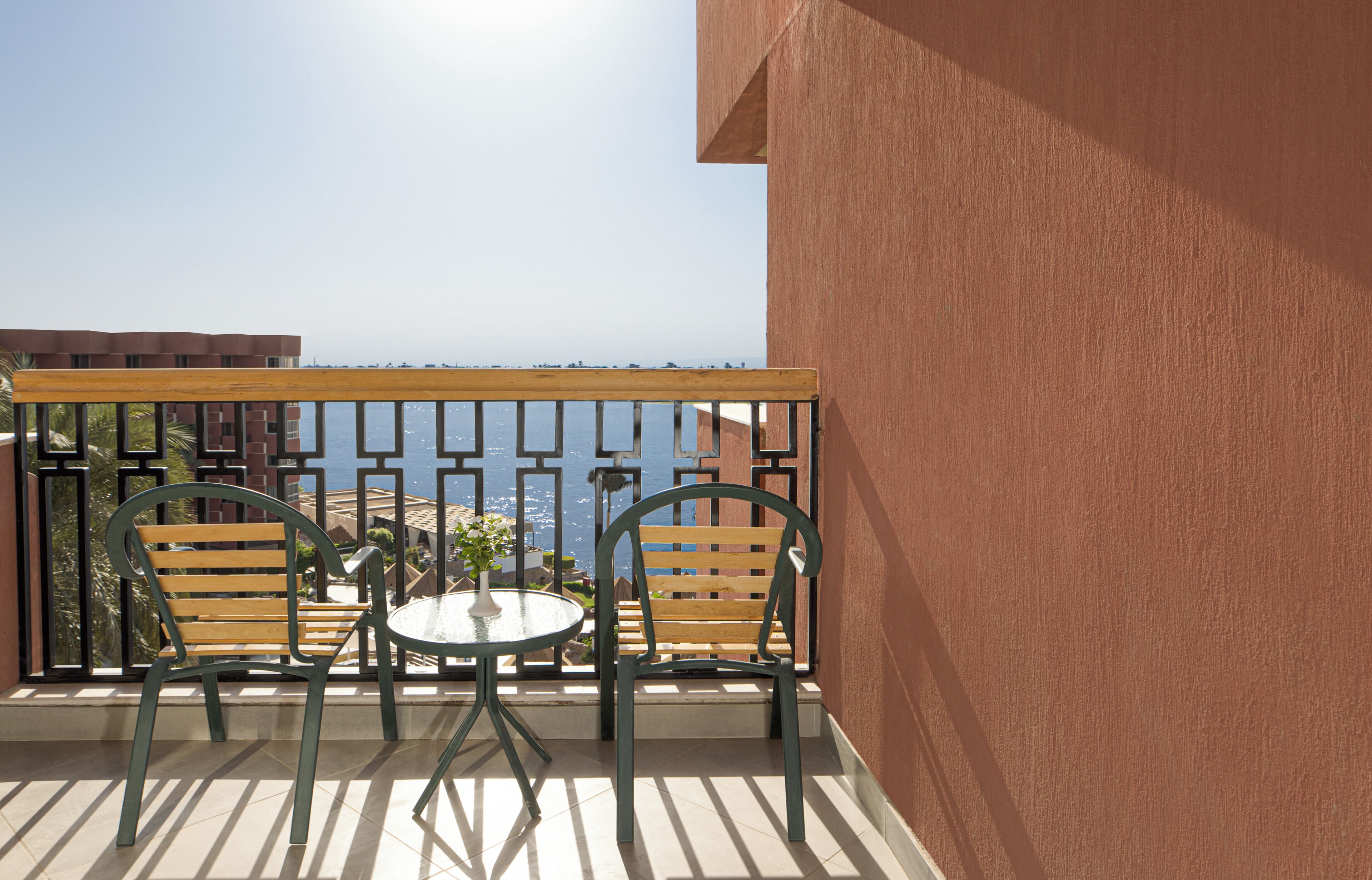 A balcony with a table and two chairs, overlooking a body of water and buildings.