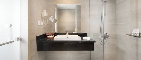 A modern bathroom with a glass-enclosed shower, a white sink, and a black countertop.