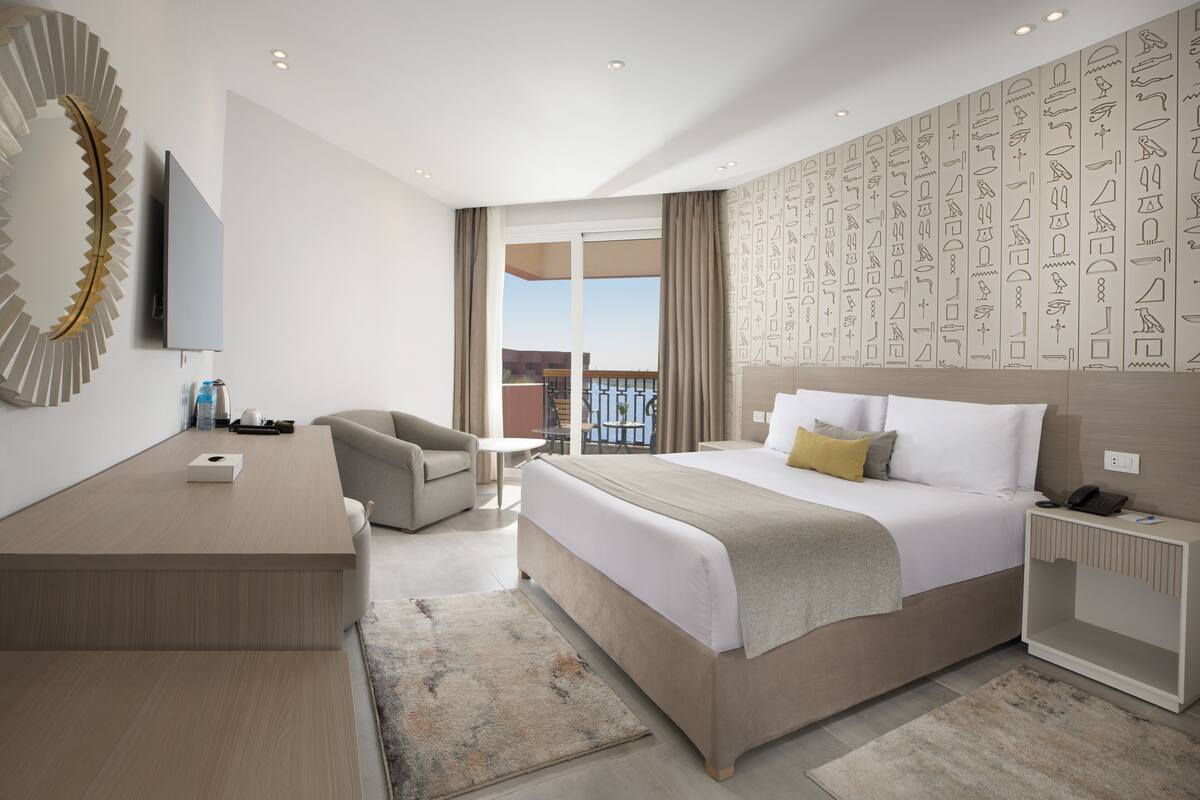 Una habitación de hotel moderna con una cama grande, un escritorio, una silla y vistas al balcón.