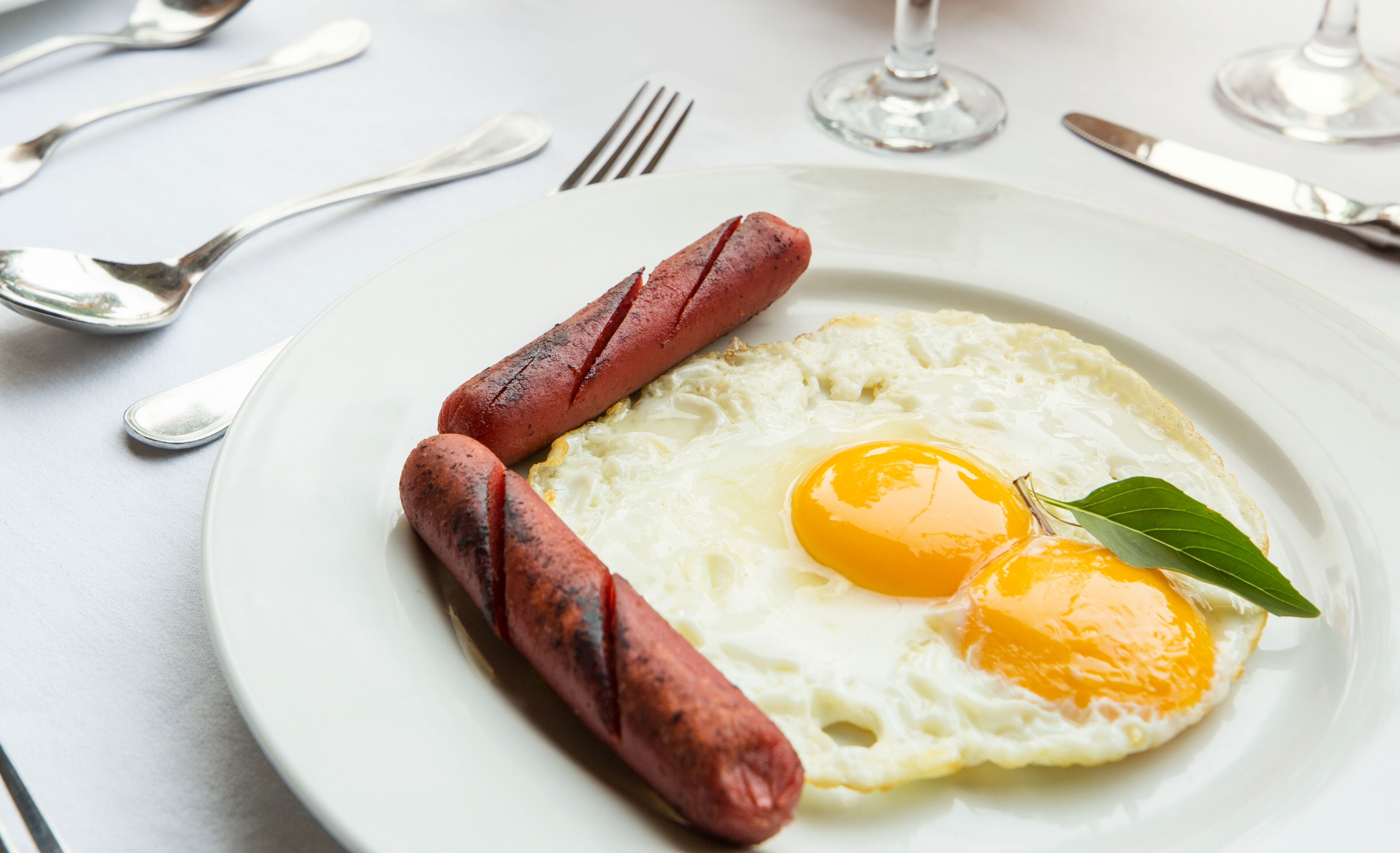 A plate with two sausages and a fried egg on a white plate.