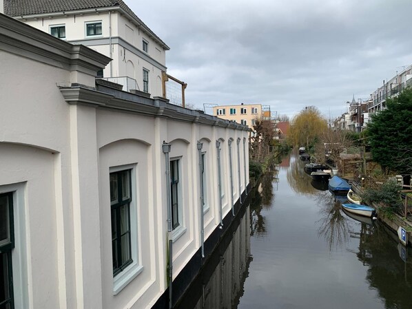 A canal with buildings on either side, a clear sky, and boats docked along the water. - Hotel Oorsprongpark (Utrecht)