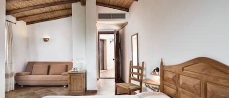 A bedroom with a wooden ceiling, a bed, a wooden chair, a nightstand, and a sofa.