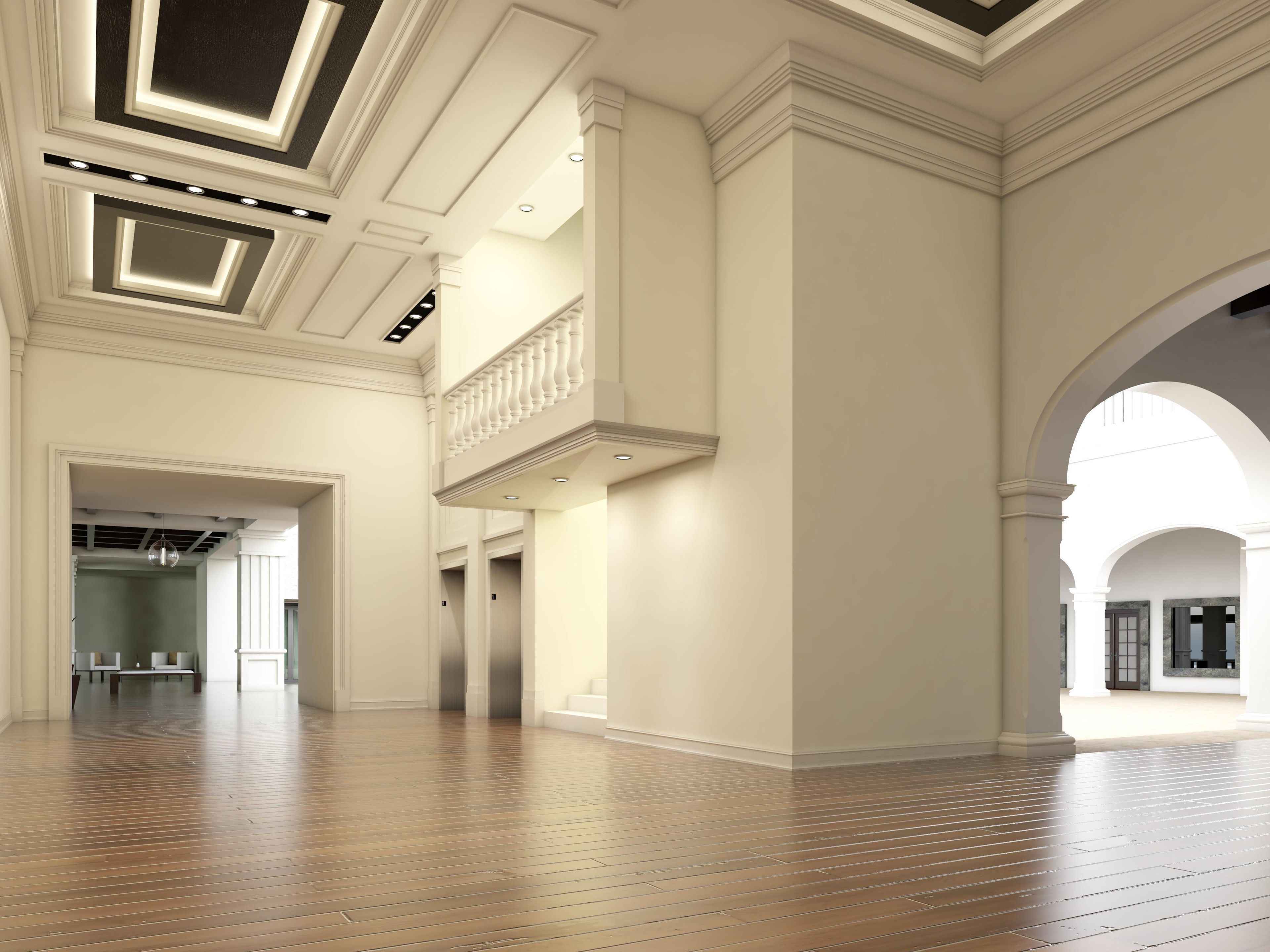 Un interior espacioso con techos altos, piso de madera y una imponente escalera.